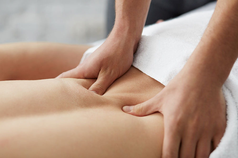 A close-up of a pair of hands giving a person a lower back massage.